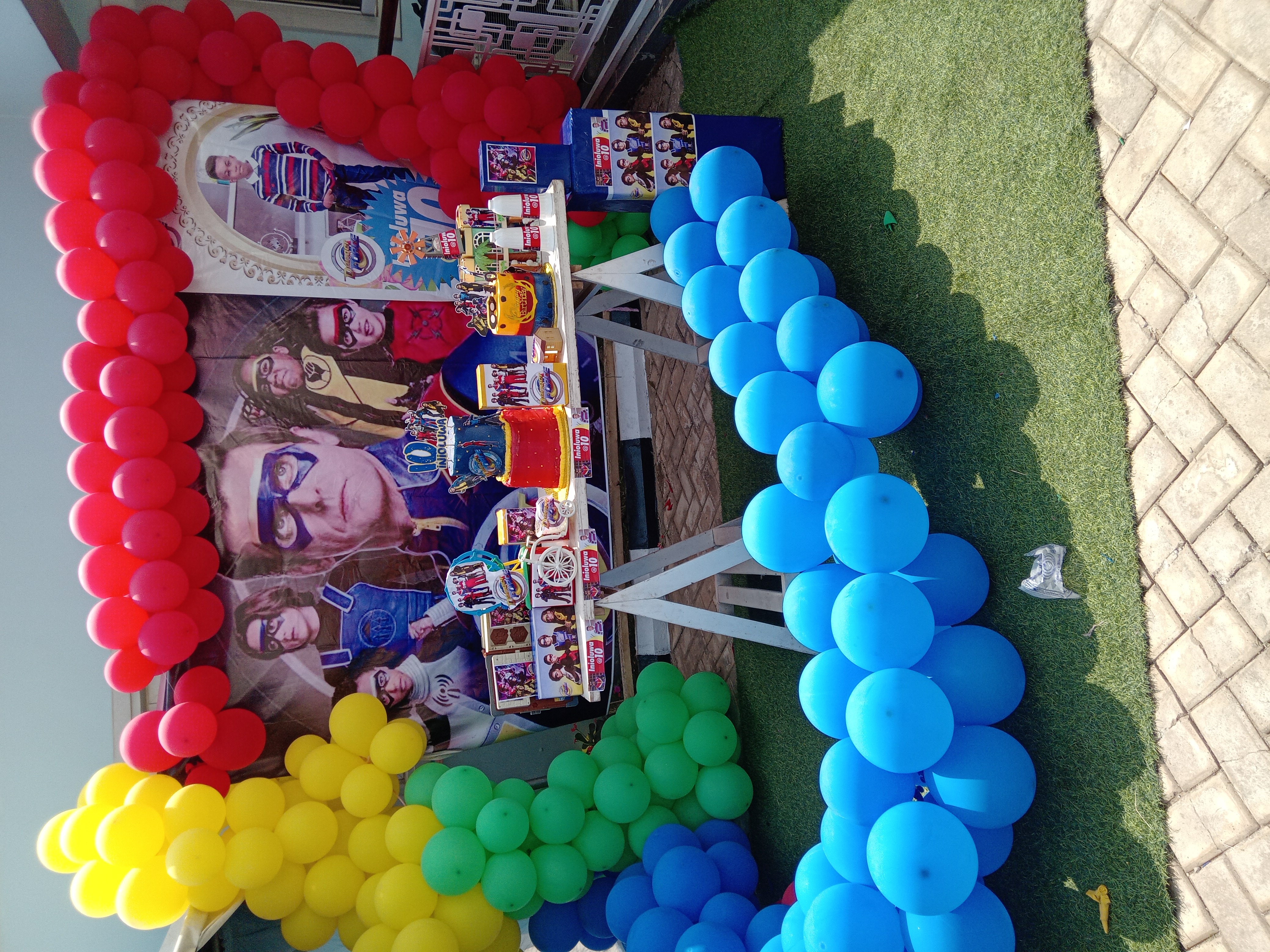 Danger Force birthday backdrop and cake table surrounded by colourful balloons