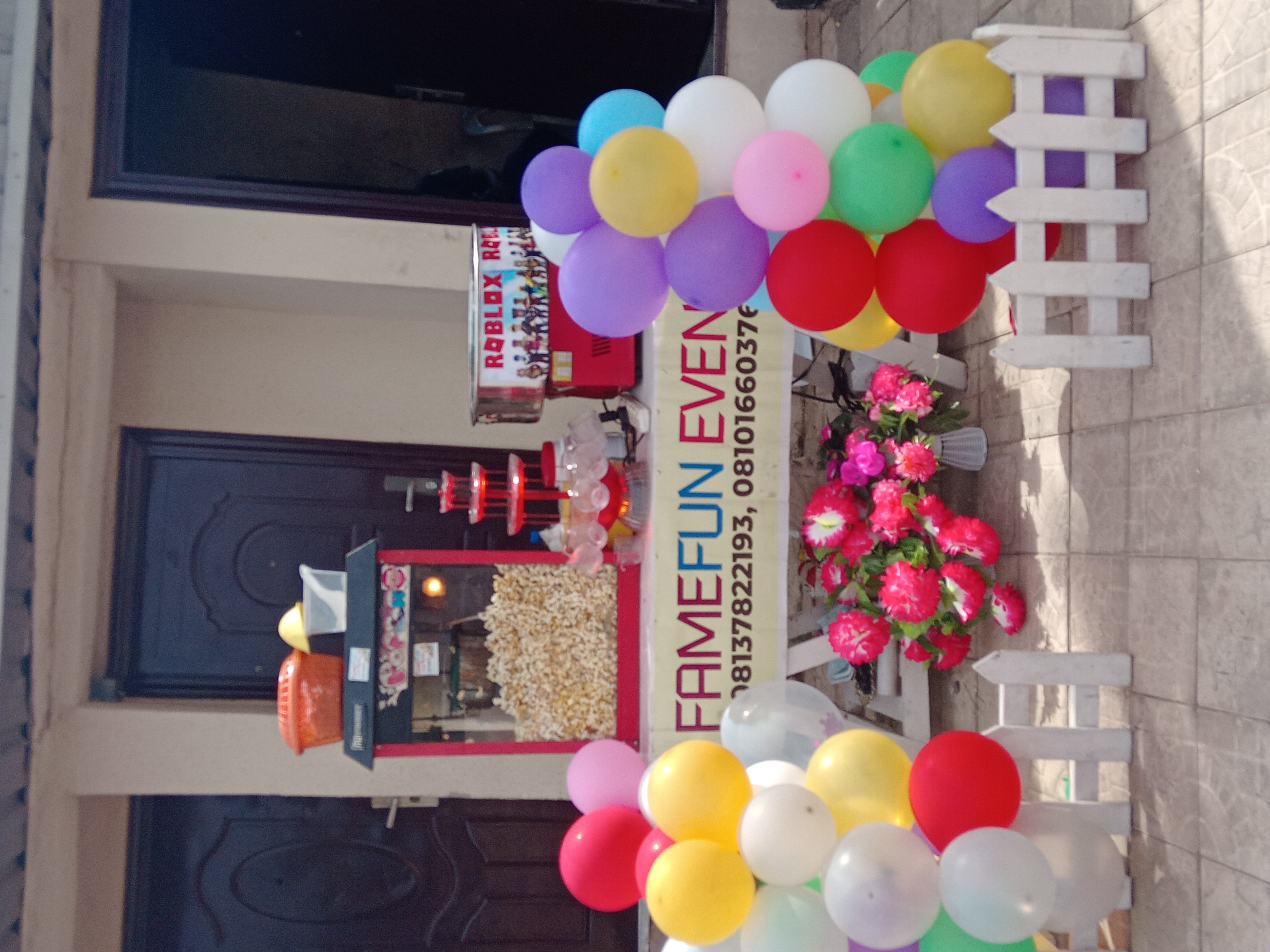 Popcorn machine, drink fountain and cotton candy machine on a party treat table with colourful balloons